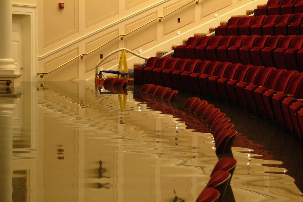 Water rises to the top of chairs inside of a flooded theater